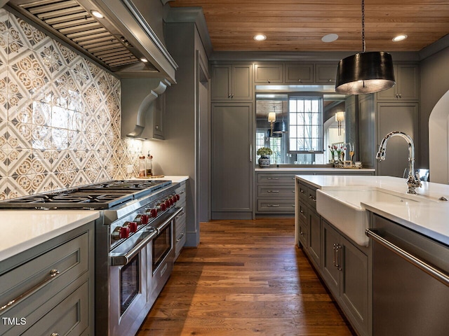 kitchen with stainless steel appliances, pendant lighting, gray cabinets, and wall chimney range hood