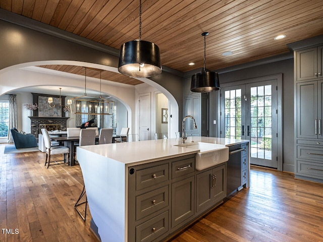 kitchen featuring arched walkways, dark wood-style flooring, light countertops, and a sink