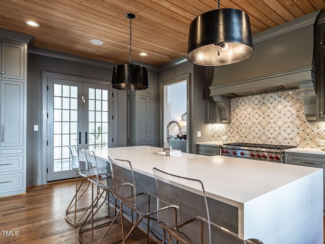 kitchen featuring pendant lighting, sink, a center island with sink, and gray cabinetry