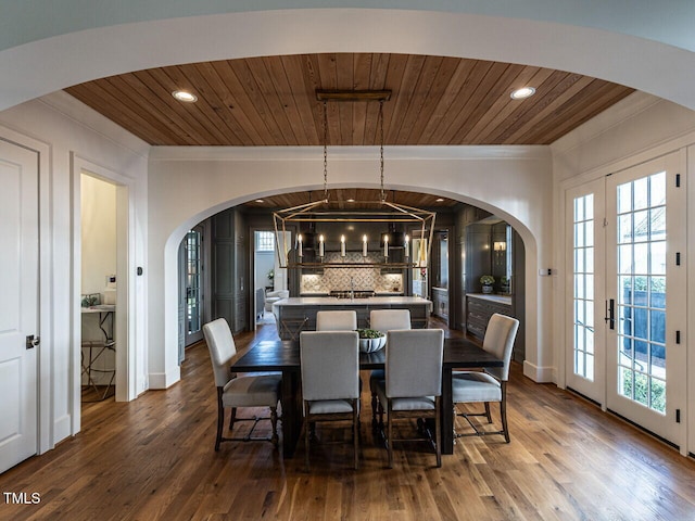 dining room featuring dark wood-style floors, ornamental molding, arched walkways, and wood ceiling