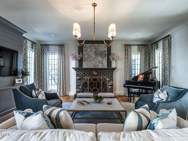 living room featuring crown molding, a healthy amount of sunlight, light hardwood / wood-style floors, and a brick fireplace