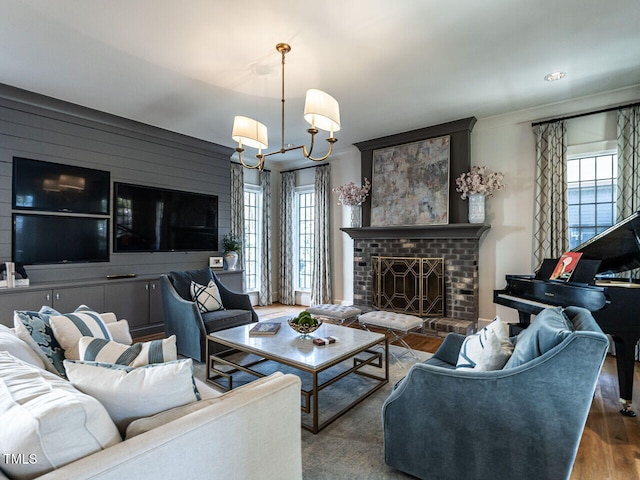 living area featuring a brick fireplace, wood finished floors, and a notable chandelier