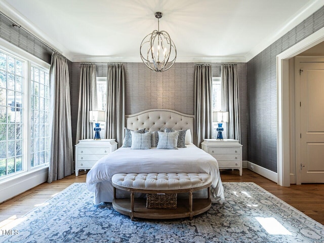 bedroom with wallpapered walls, multiple windows, baseboards, and wood finished floors