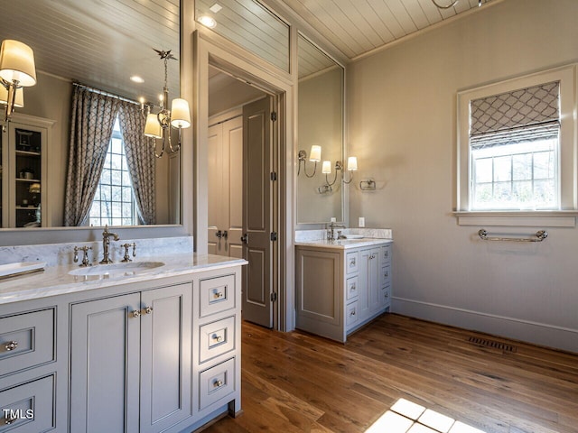 full bath featuring wooden ceiling, two vanities, a sink, and wood finished floors