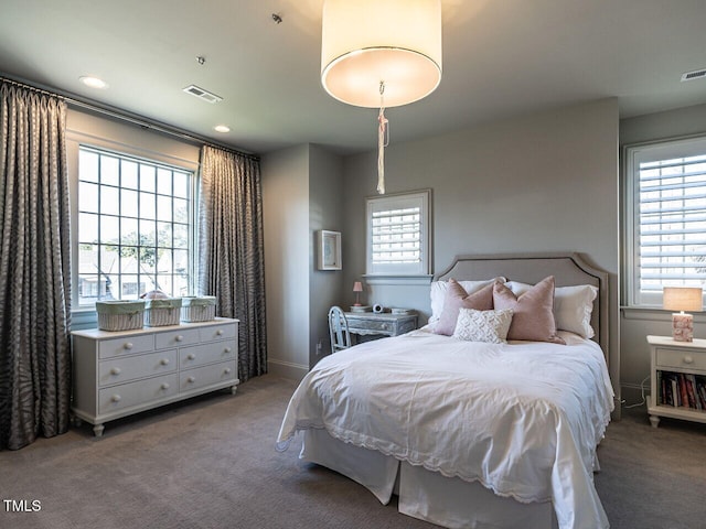 carpeted bedroom featuring multiple windows, recessed lighting, visible vents, and baseboards