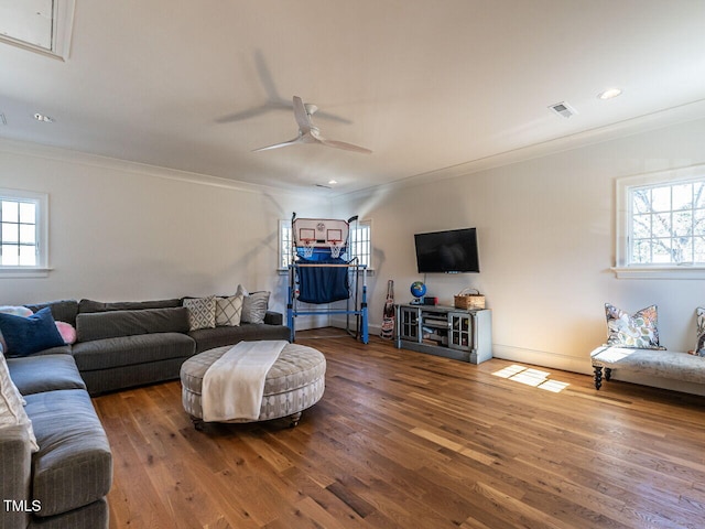 living room with a healthy amount of sunlight, crown molding, visible vents, and wood finished floors