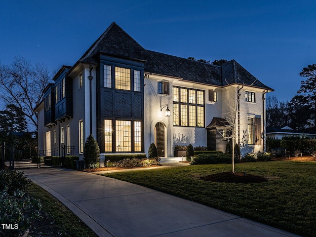 french country inspired facade with a high end roof, brick siding, and a front yard