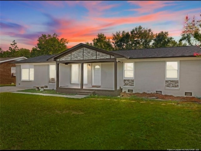 back house at dusk with a lawn