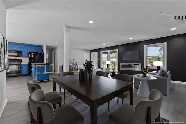 dining area featuring light hardwood / wood-style flooring, a healthy amount of sunlight, and ornate columns