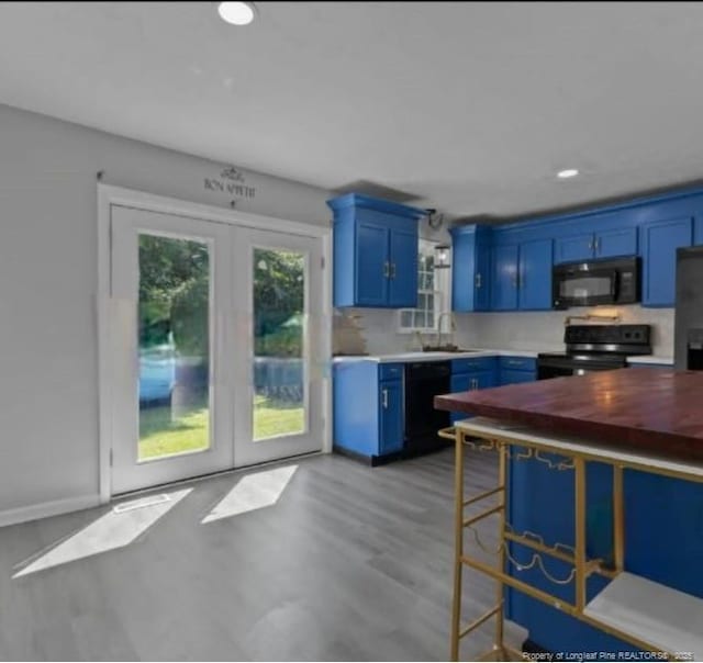 kitchen with blue cabinetry, french doors, sink, light hardwood / wood-style floors, and black appliances