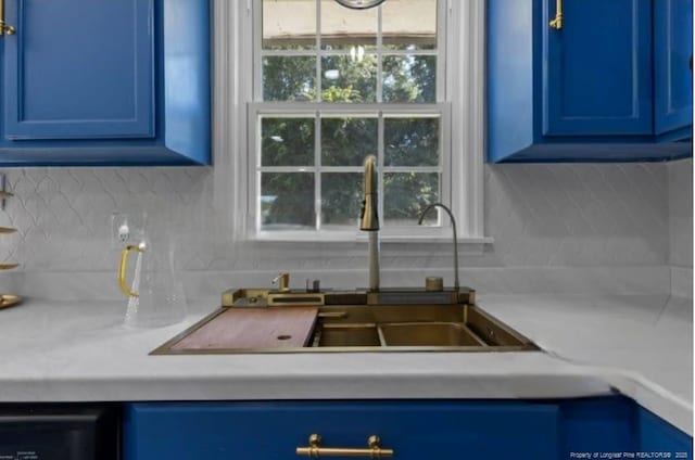 interior details featuring blue cabinetry, sink, and tasteful backsplash