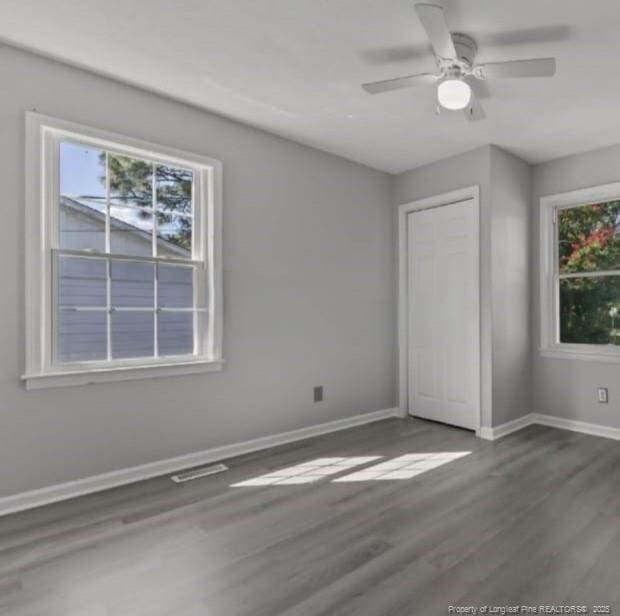 unfurnished bedroom featuring a closet, dark hardwood / wood-style floors, and multiple windows