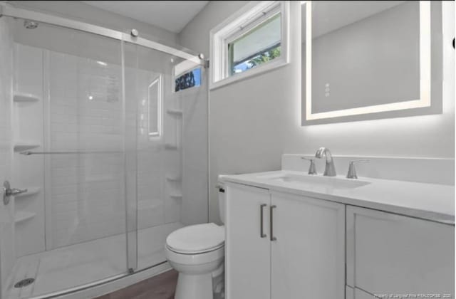 bathroom featuring walk in shower, vanity, and toilet