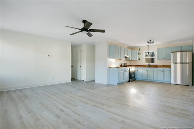 kitchen featuring butcher block counters, sink, hanging light fixtures, light wood-type flooring, and appliances with stainless steel finishes