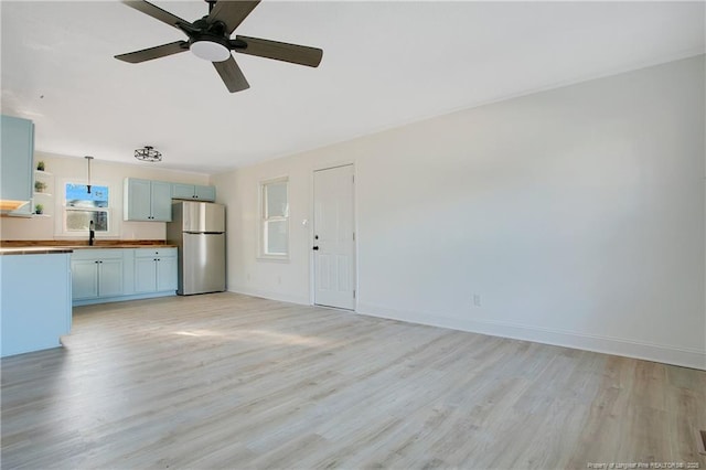 unfurnished living room with sink, light hardwood / wood-style flooring, and ceiling fan