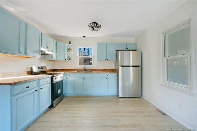 kitchen with blue cabinetry, sink, wooden counters, appliances with stainless steel finishes, and pendant lighting