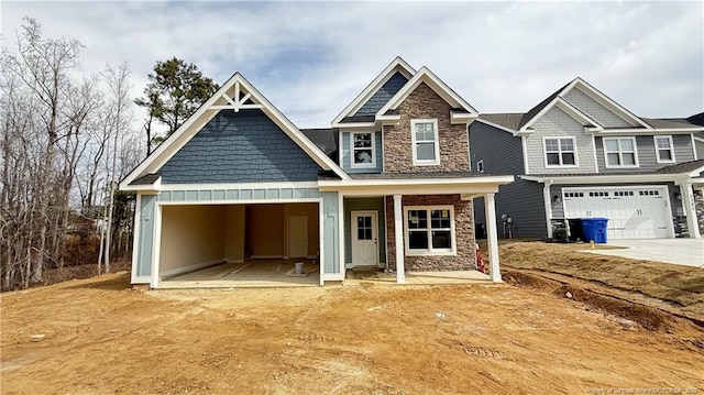 craftsman house with a garage, stone siding, and driveway