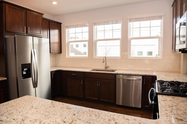 kitchen with light stone counters, sink, backsplash, and appliances with stainless steel finishes