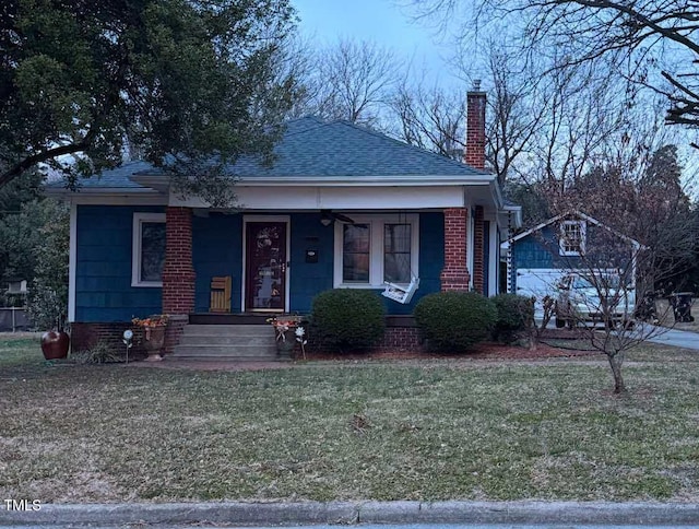 bungalow with a porch and a front lawn