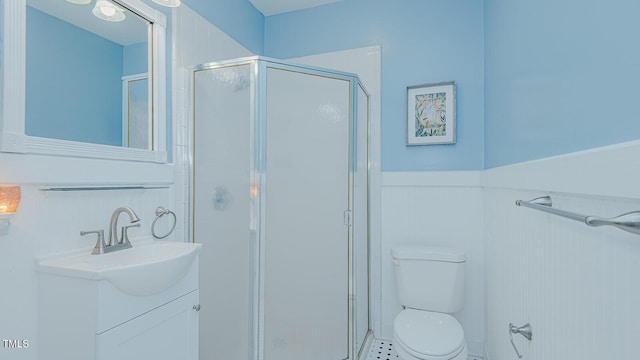 full bath with toilet, a wainscoted wall, vanity, and a stall shower