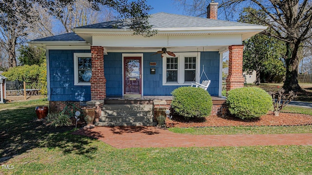 bungalow featuring a porch, a shingled roof, a chimney, and a ceiling fan