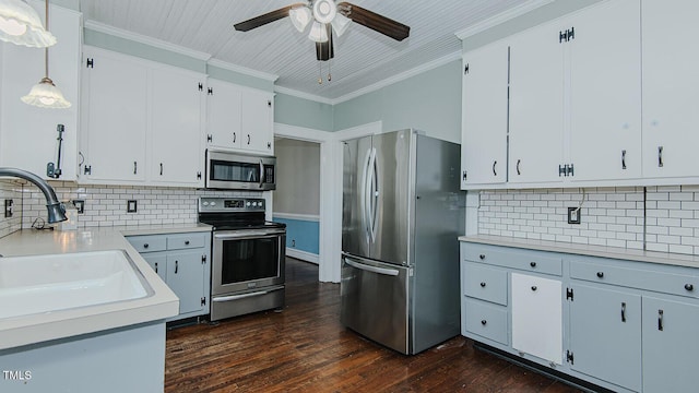 kitchen with dark wood-style floors, ornamental molding, stainless steel appliances, light countertops, and a sink