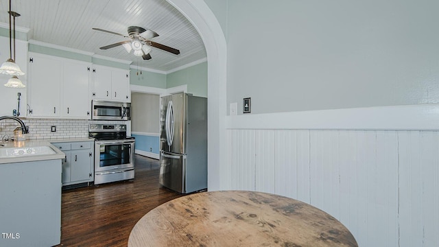 kitchen with dark wood-type flooring, a sink, light countertops, ornamental molding, and appliances with stainless steel finishes