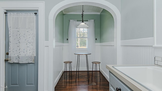 interior space with dark wood-style flooring, a wainscoted wall, and crown molding