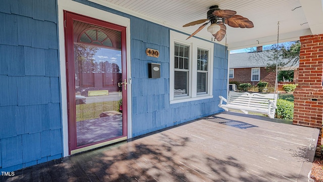 view of exterior entry with ceiling fan and a porch