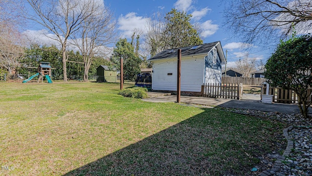 view of yard with fence, a playground, and an outdoor structure