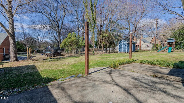 view of yard featuring a playground, an outdoor structure, a fenced backyard, and a shed