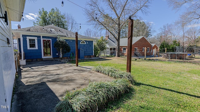 view of yard with driveway, a trampoline, a patio area, and fence