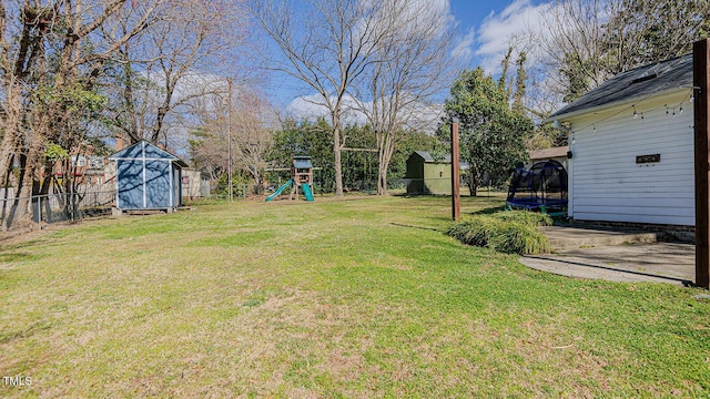 view of yard featuring a playground, a fenced backyard, an outdoor structure, a shed, and a trampoline