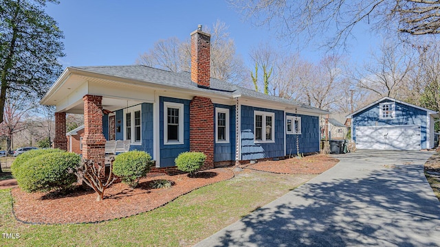 exterior space featuring a garage, roof with shingles, a chimney, and an outdoor structure