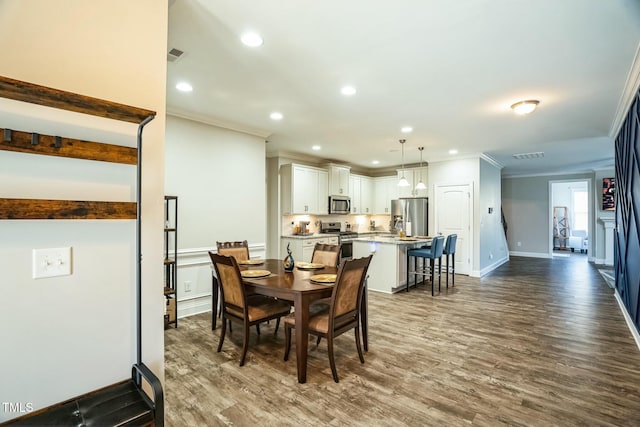 dining area featuring hardwood / wood-style flooring and crown molding