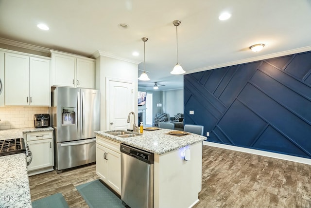 kitchen featuring sink, white cabinets, hanging light fixtures, stainless steel appliances, and crown molding