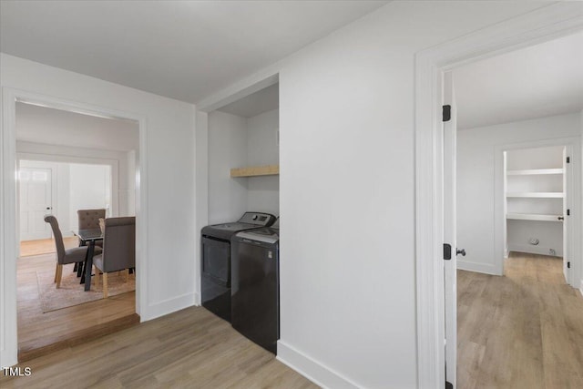 laundry area featuring separate washer and dryer and light hardwood / wood-style flooring