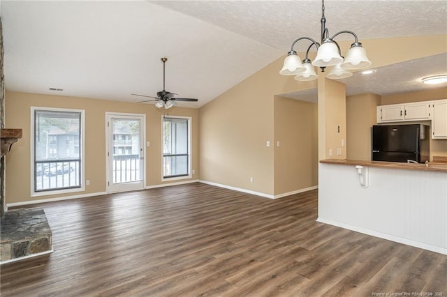 unfurnished living room featuring vaulted ceiling, a textured ceiling, dark hardwood / wood-style flooring, a fireplace, and ceiling fan with notable chandelier