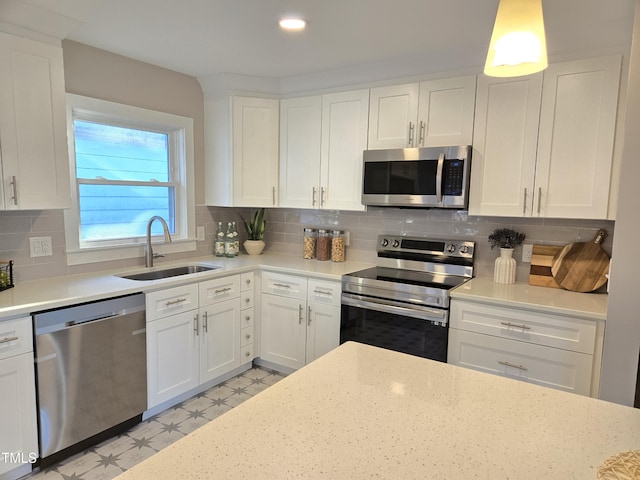 kitchen featuring sink, tasteful backsplash, stainless steel appliances, light stone countertops, and white cabinets