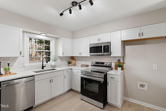 kitchen with stainless steel appliances, tasteful backsplash, sink, and white cabinets