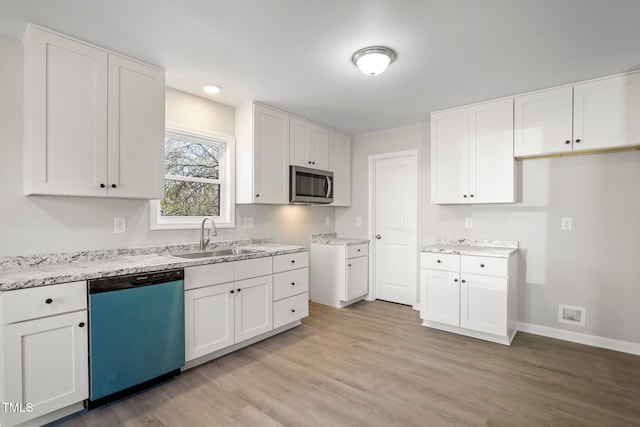 kitchen with stainless steel appliances, sink, white cabinets, and light hardwood / wood-style flooring