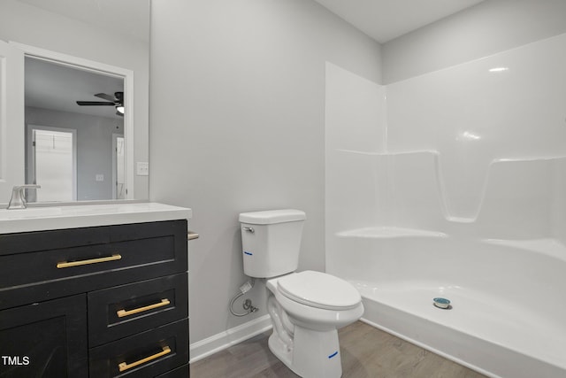 bathroom with hardwood / wood-style flooring, vanity, walk in shower, and toilet