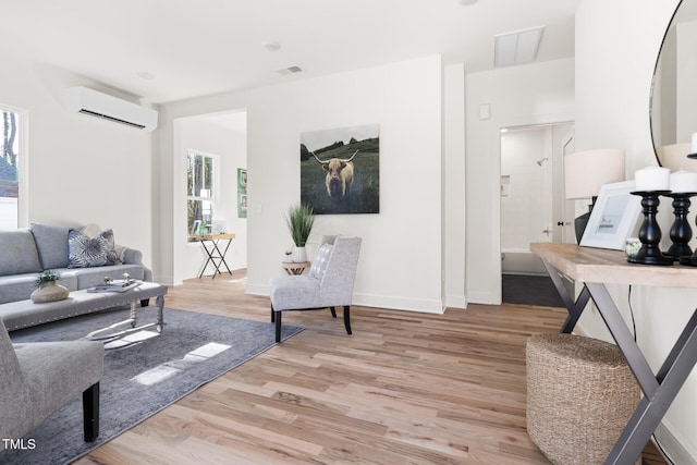 living room with a wall mounted air conditioner and light hardwood / wood-style floors