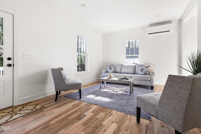 living room with a wall mounted air conditioner and light wood-type flooring