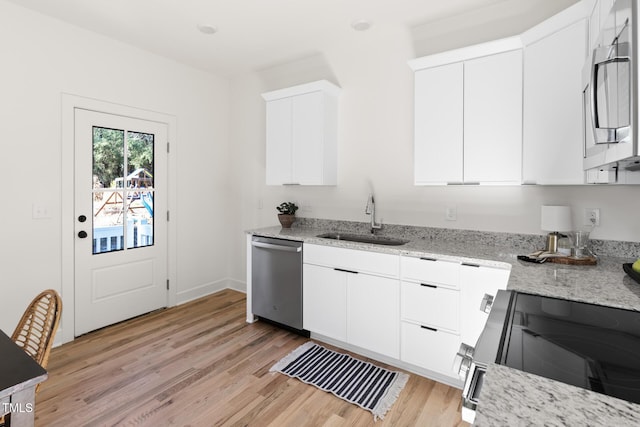 kitchen with sink, appliances with stainless steel finishes, light stone countertops, light hardwood / wood-style floors, and white cabinets