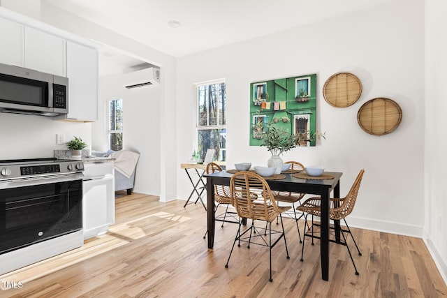 dining space with a wall unit AC and light hardwood / wood-style floors