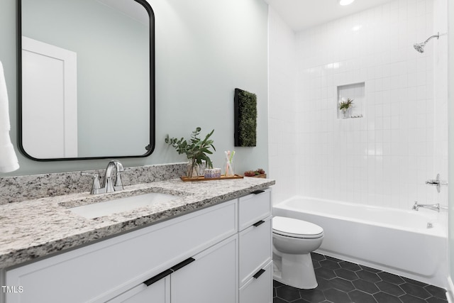 full bathroom featuring tile patterned flooring, vanity, tiled shower / bath, and toilet