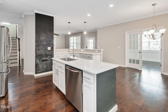 kitchen with pendant lighting, sink, white cabinetry, stainless steel appliances, and an island with sink