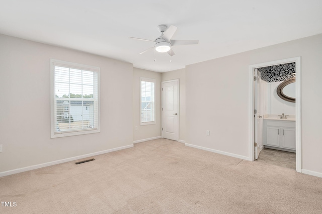 unfurnished bedroom featuring sink, light carpet, and ceiling fan