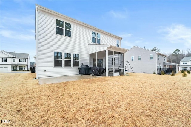 back of house featuring a lawn, a sunroom, and a patio